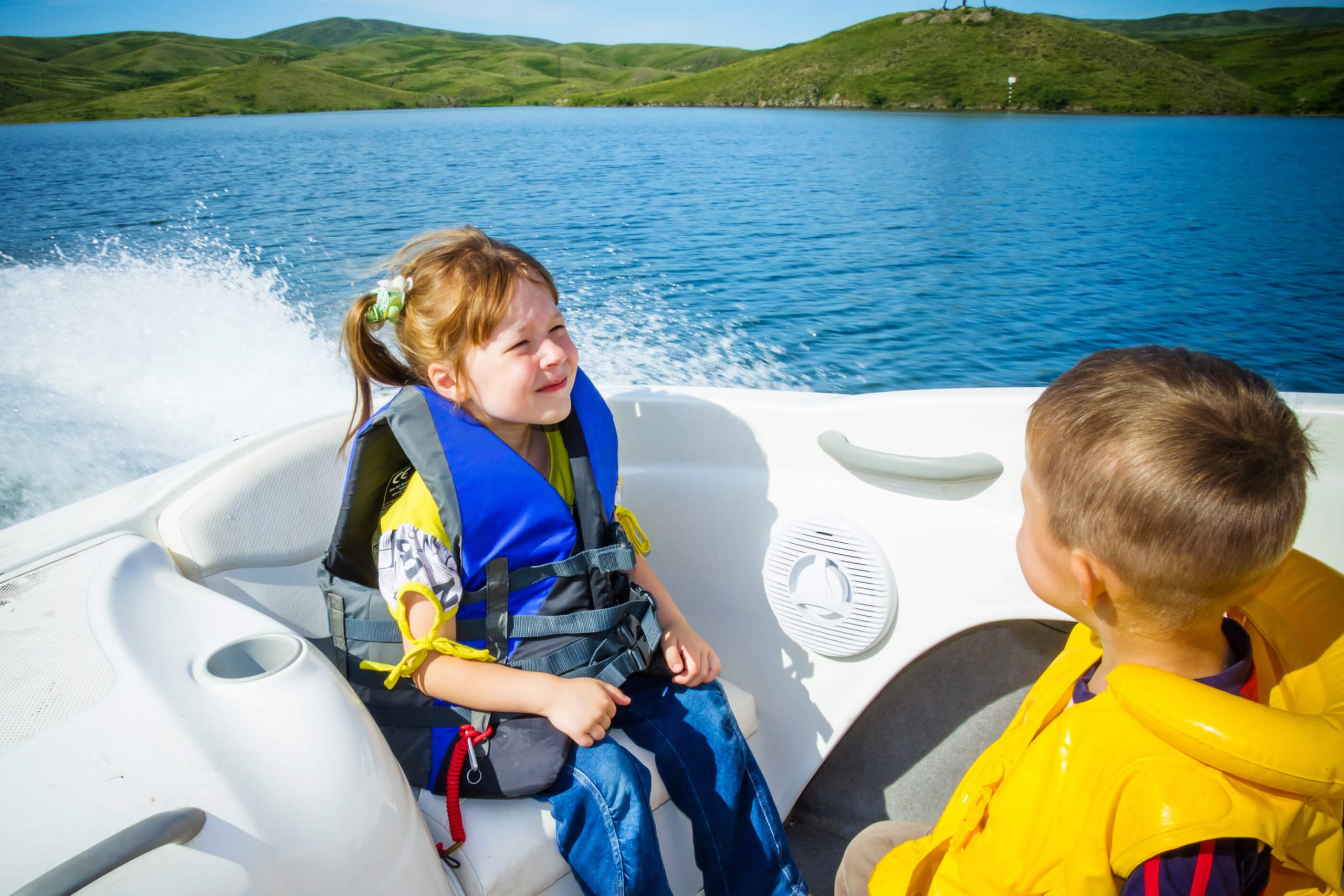 two kids on a boat wearing lifejackets for boating safety