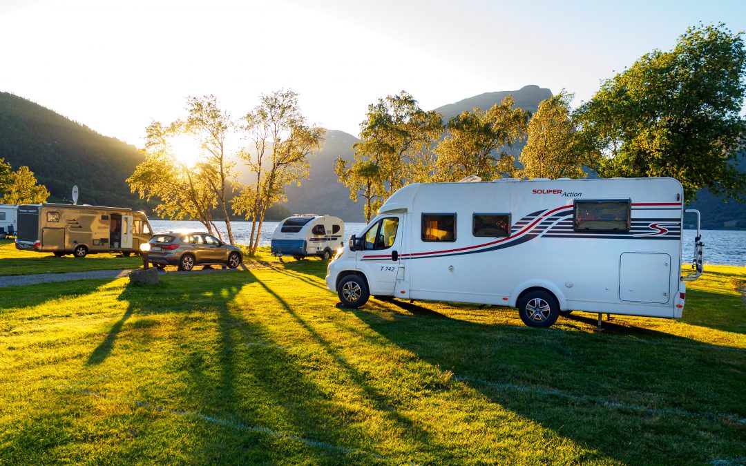 RVs parked by the water in a grass field