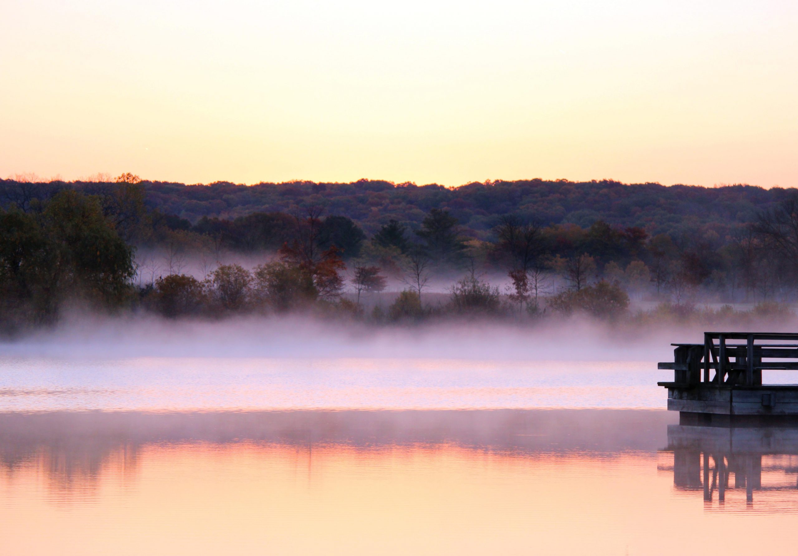 sunrise over a misty lake and pier in wisconsin